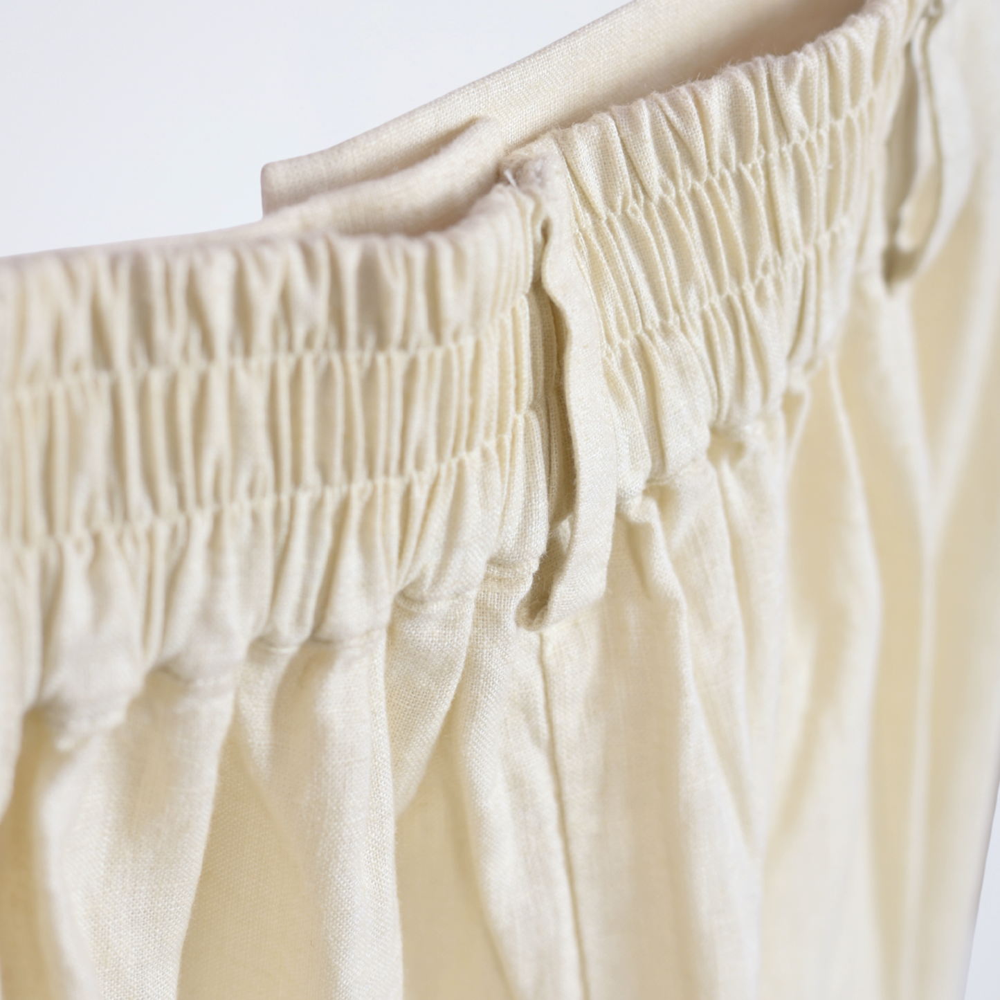 Pearl white linen pants with soft pleats and a stretch waist. Lightweight, breathable, and roomy for comfort and movement