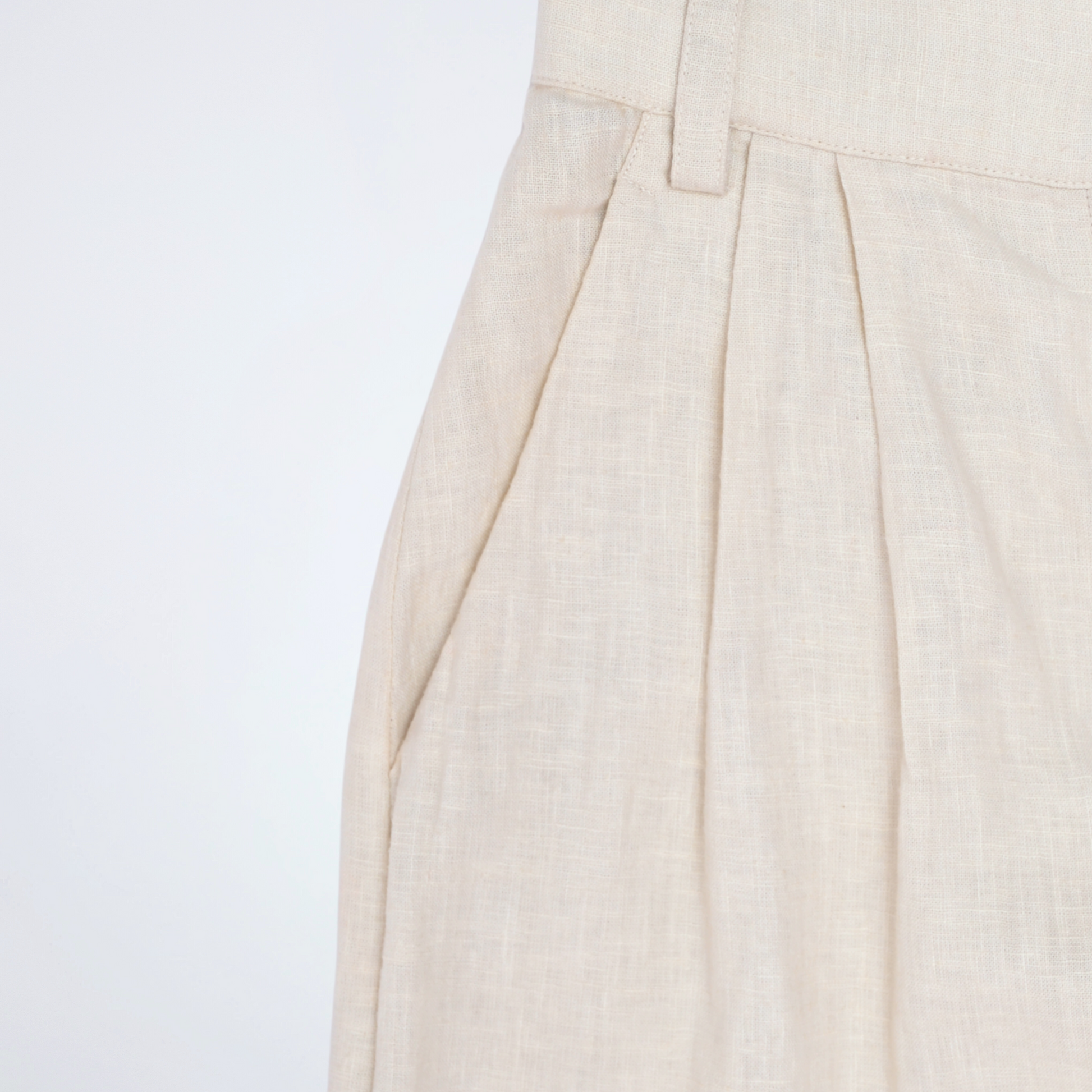 Pearl white linen pants with soft pleats and a stretch waist. Lightweight, breathable, and roomy for comfort and movement