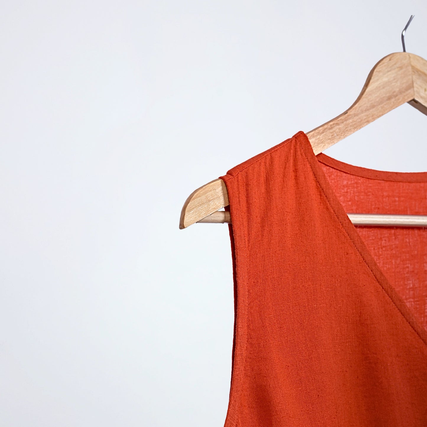 Sleeveless linen dress with pleated wrap fall. Breathable, relaxed, and fluid for moving forward with ease