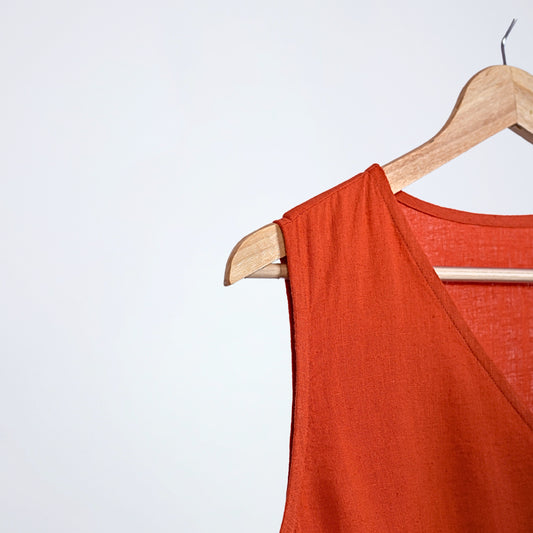 Sleeveless linen dress with pleated wrap fall. Breathable, relaxed, and fluid for moving forward with ease
